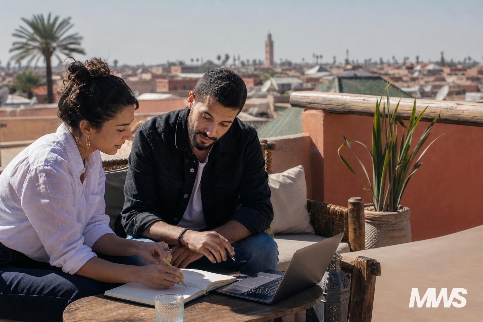 Deux marketeurs collaborent sur une terrasse à Marrakech, vue sur les toits